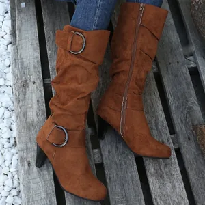 Close-up of brown suede slouchy mid-calf high heel boots with metal buckle strap detail
