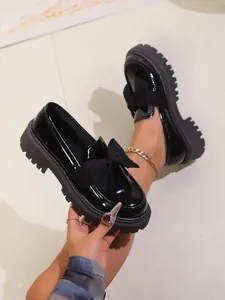 Detailansicht eleganter schwarzer Lackleder-Loafers mit Schleife und Plateausohle