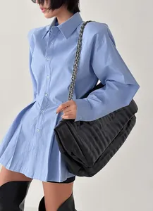 Detailed view of a blue pleated cotton shirt styled with a large black quilted bag.