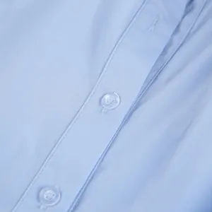 Macro detail of a light blue cotton shirt showing front buttons and fabric texture