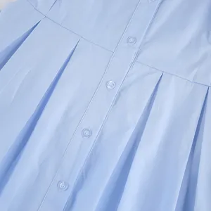 Close-up detail of a light blue cotton shirt showing front buttons and pleated waistline