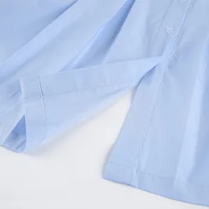 Detailed close-up of light blue cotton shirt hem showing fine stitching and fabric texture