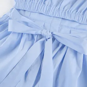 Macro detail of a light blue cotton shirt featuring an adjustable waist bow tie