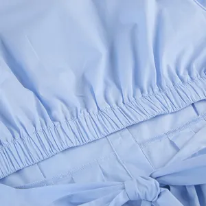 Detail shot of light blue cotton shirt with elastic shirring and a tied waist bow.