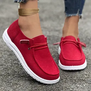 Primo piano di mocassini in velluto a coste rosse da donna con suole bianche e lacci elastici.