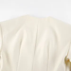 Detailopname van de achterhals en gestructureerde schoudervullingen van de crème blazer.