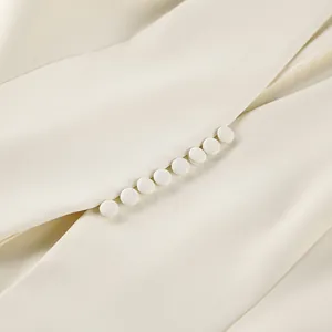 Detailopname van elegante stoffen knopen op een getailleerde crèmekleurige blazer