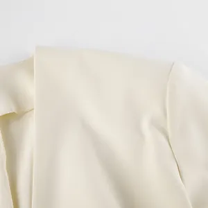 Detailopname van de schouder van een crèmewitte blazer met schoudervulling en stiksel