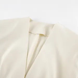 Detailweergave van een crèmewitte blazer met V-hals, gewatteerde schouders en strakke naden
