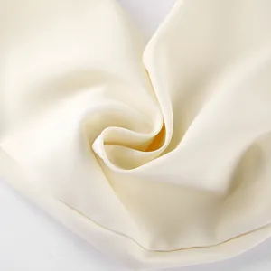Detailopname van de hoogwaardige roomwitte blazerstof met een fijne weving en soepele val.