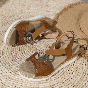 Detailed view of women's brown wedge sandals with metallic ring decoration.
