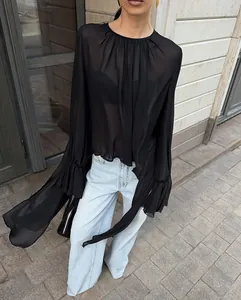 Gedetailleerd overzicht van een chique zwarte chiffon blouse met ruches aan de mouwen.