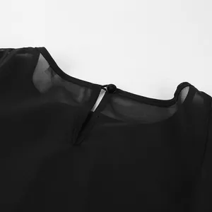 Detail van de halslijn van een zwarte chiffon blouse met mesh en knoopsluiting.