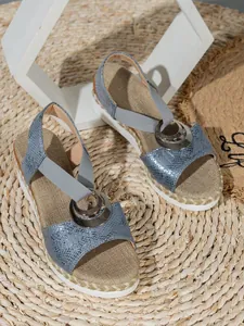 Detail view of blue snakeskin wedge sandals with metallic ring and jute-wrapped sole