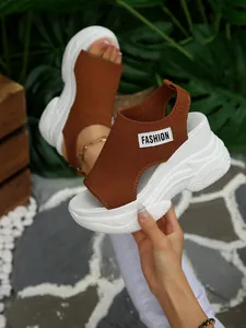Detail van een bruine gebreide sandaal met witte dikke plateauzool en 'FASHION'-label