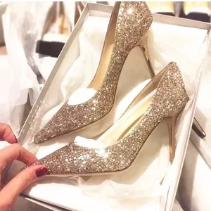 Sparkling gold sequin pointed-toe stiletto high heels presented in a white shoe box