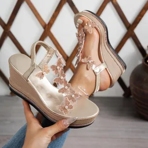 Close-up of wedge sandals with transparent PVC upper and elegant butterfly pearl appliques.