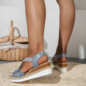 Detailed view of women's snakeskin wedge sandals with elastic straps and woven sole