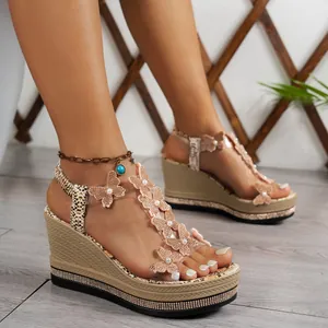 Close-up of butterfly wedge sandals featuring pearl accents and rhinestone platform