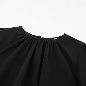 Detailopname van de halslijn van een zwarte chiffon blouse met mooie fijne plooien.