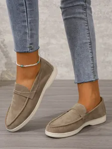 Detailansicht von khakifarbenen Wildleder-Loafers für Damen mit Jeans und Fußkettchen