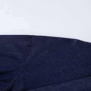 Close-up detail of orange contrast stitching on dark blue soft cotton denim fabric garment