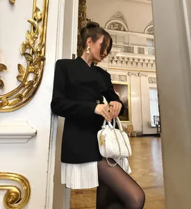 Gros plan d'un blazer noir rétro avec un élégant détail de base plissée blanche