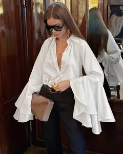 Detalle de una elegante blusa de satén blanco con mangas acampanadas y cuello clásico