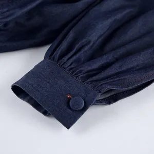 Close-up of soft blue cotton denim puff sleeve cuff featuring a fabric-covered button detail