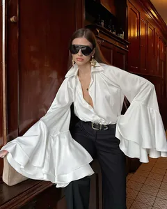 Detalle de blusa de satén blanco con mangas de campana dramáticas de estilo francés.