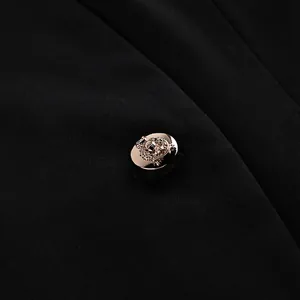 Gros plan d'un bouton décoratif à blason doré sur un tissu de veste de costume noir