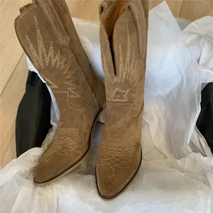 Detailed view of brown suede western cowboy boots with intricate embroidery in a gift box