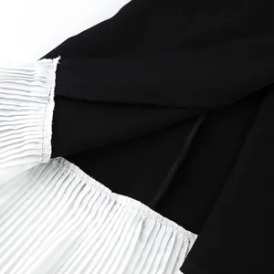 Gros plan d'un blazer noir avec détails plissés contrastés blancs et coutures fines