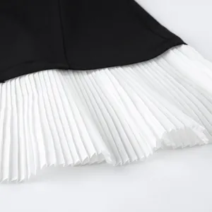 Gros plan d'un blazer noir de style vintage avec un ourlet plissé en mousseline blanche