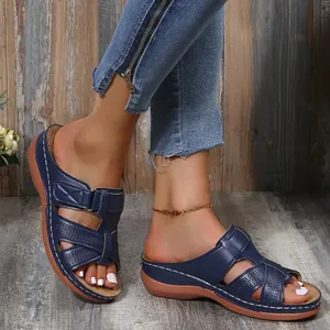 Vue détaillée de sandales compensées bleu marine avec motif ajouré et bride velcro sur pieds