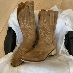 Close-up of retro brown suede Western cowboy boots with star embroidery in a package box.