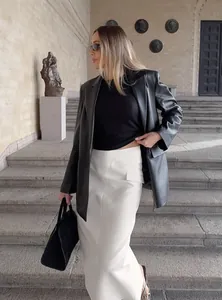 Elegant white high-waisted straight skirt styled with a black blazer on stone steps