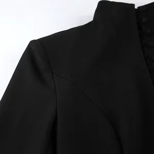 Detail view of a black blazer dress featuring a stand collar and elegant covered buttons.