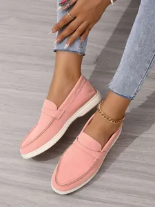 Detailansicht von rosa Wildleder-Loafers an den Füßen mit stilvollem Fußkettchen
