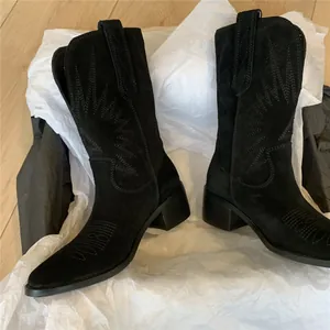 Detailed view of black suede western cowboy boots with intricate embroidery and V-cut.
