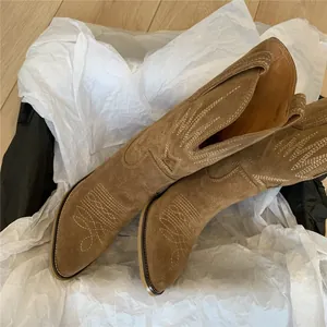 Detailed close-up of brown suede western cowboy boots featuring vintage embroidery