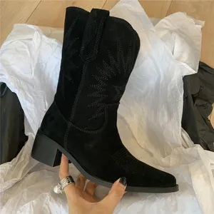 Detailed side view of black suede western boots with intricate vintage star embroidery