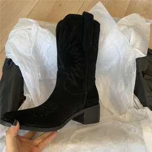 Close-up of a black suede Western cowboy boot featuring intricate tonal embroidery details.