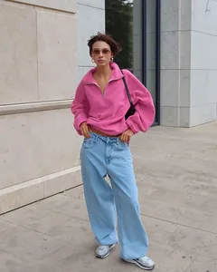 Ganzkörperansicht einer Frau in einem leuchtend rosa Fleece-Sweatshirt und hellblauen Jeans