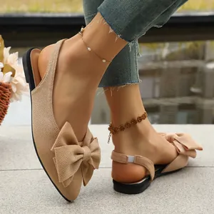 Elegant beige pointed-toe flat sandals with a large decorative bow and slingback strap