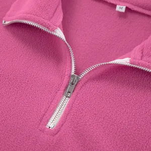 Nahaufnahme eines rosa Fleece-Sweatshirts mit halbem Reißverschluss und weichem Stoffdetail