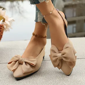 Elegant beige pointed-toe flat sandals for women featuring a large decorative bow tie.