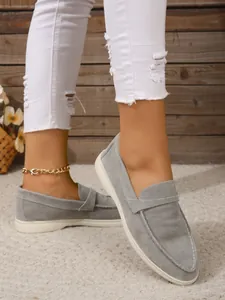 Nahaufnahme von grauen Wildleder-Loafers mit spitzen Zehen und flachen weißen Sohlen