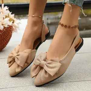 Close-up of elegant beige pointed toe flat slingback sandals with a large bow