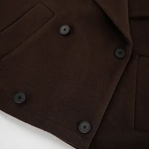 Detailopname van een donkerbruine wollen jas met dubbele rij knopen en stoffen textuur.
